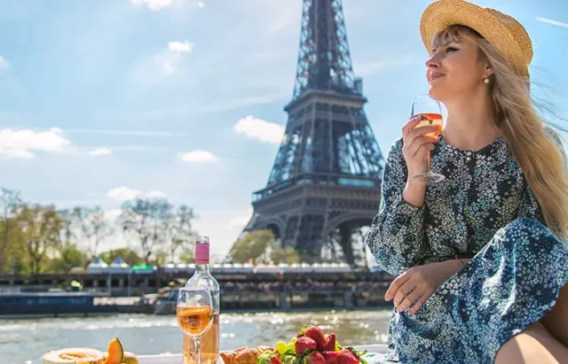 A woman near the Eiffel Tower drinks wine