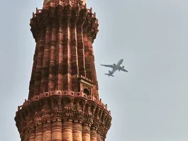 Qutb Minar minaret with airplane in sky background