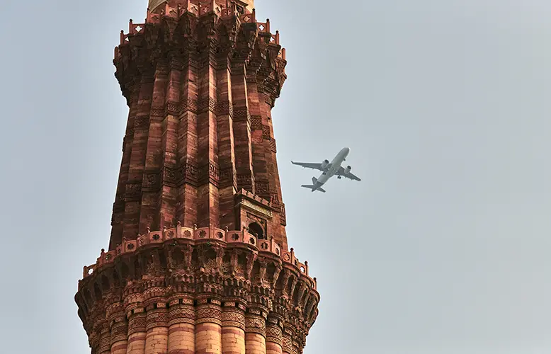 Qutb Minar minaret with airplane in sky background