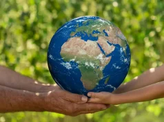 Eco-Friendly Escapes: EarthCheck Certification man and child holding blue planet earth in hands against spring green background