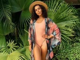 woman in straw hat and summer stylish outfit posing in tropical garden