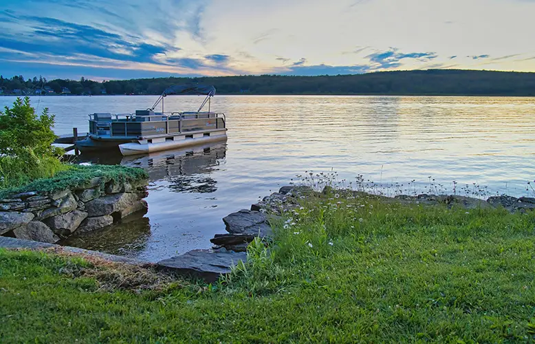 A boat docked on a shore on a lake and sunset in Connecticut