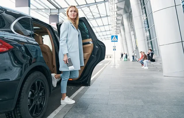 Woman with boarding ticket in her hand leaving car