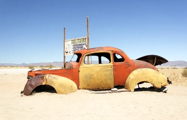 abandoned-car-by-information-sign-against-clear-sky copy
