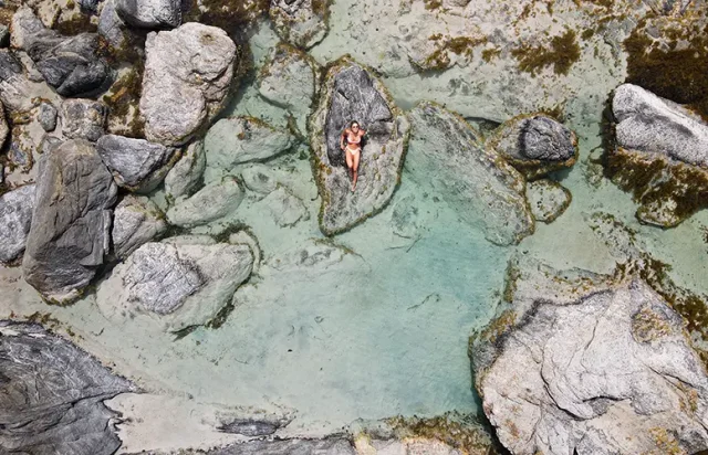 aerial-view-of-a-woman-resting-on-a-rock-at-the-po-2025-02-09-20-09-57-utc copy