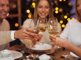 Friends celebrating christmas party holding wine