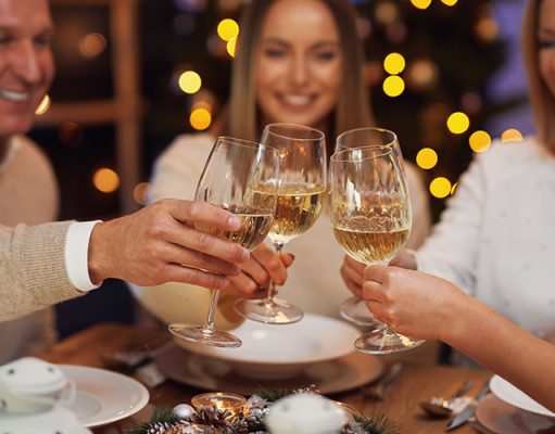 How to Make Hosting Dinner Less Stressful (Even on a Weeknight) Friends celebrating christmas party holding wine