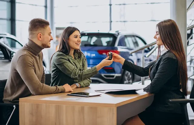 young-couple-talking-sales-person-car-showroom copy