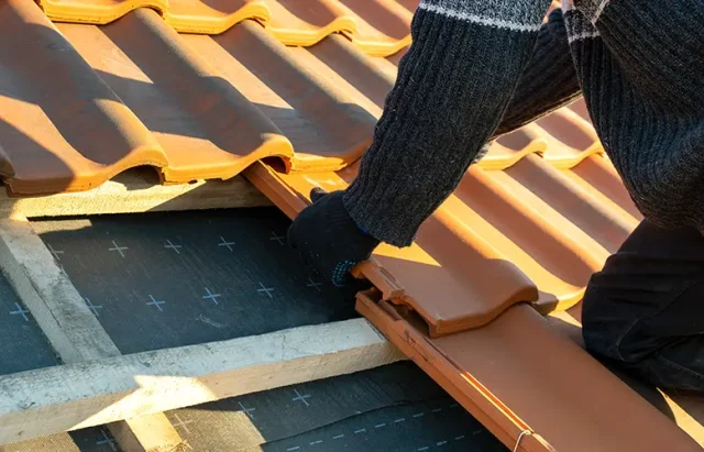 closeup-worker-hands-installing-yellow-ceramic-roofing-tiles-mounted-wooden-boards-covering-residential-building-roof-construction copy