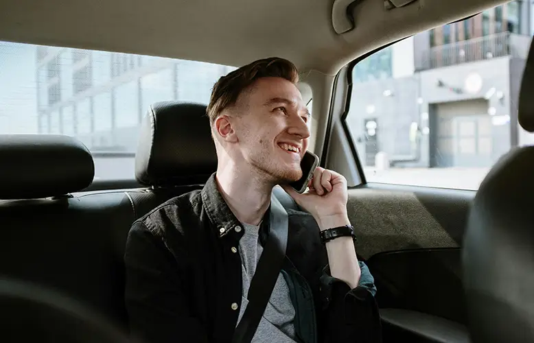 A man sitting in the backseat of the car, talking on the phone
