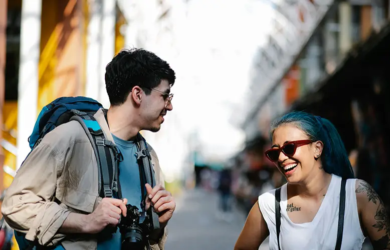 A man with a camera talking to a woman who is laughing