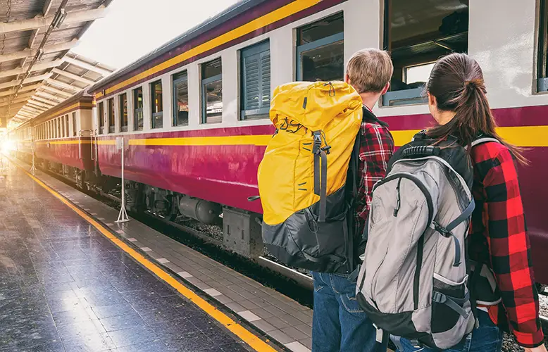 Two people carrying backpacks, waiting for the train