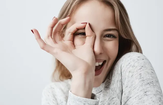 young-european-joyful-blonde-female-looking-through-fingers-ok-gesture-woman-casual-clothes-smiling-broadly-her-happy-face-expression-proves-everything-goes-according-plan copy