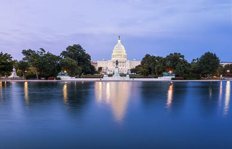 church-by-river-city-against-sky-dusk copy : Illuminated U.S. Capitol building at night in Washington DC, a top highlight for visitors planning things to do in Washington DC in one day