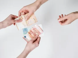 Overhead shot of three hands exchanging various Euro banknotes
