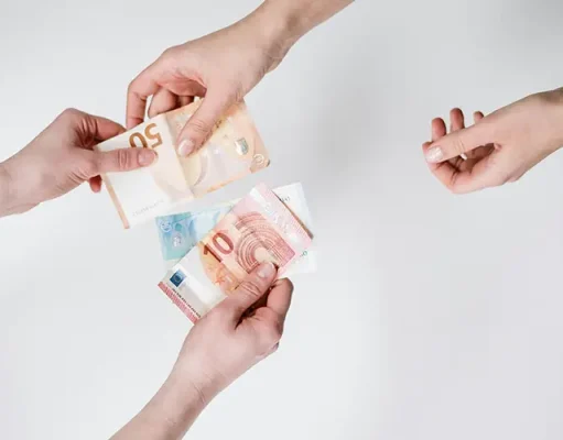 International Money Transfers Made Easy for Travelers Overhead shot of three hands exchanging various Euro banknotes