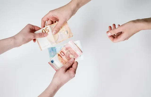 pexels-cottonbro-3943726 copy Overhead shot of three hands exchanging various Euro banknotes