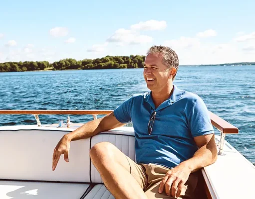 Boat Ownership vs. Club Access: The Busy Leader’s Choice Smiling man relaxing on a boat in Florida waters, enjoying hassle-free boating without ownership on a sunny day.