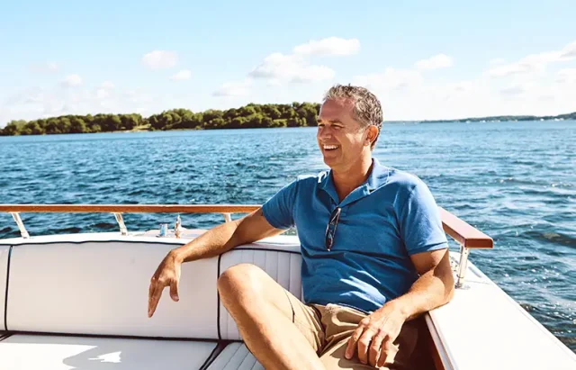 thinking-mature-man-boat-vacation-travel-sailing-ideas-adventure-journey-ocean-transport-smile-person-retirement-relax-yacht-ship-holiday-cruise-outdoor-sea copy Smiling man relaxing on a boat in Florida waters, enjoying hassle-free boating without ownership on a sunny day.