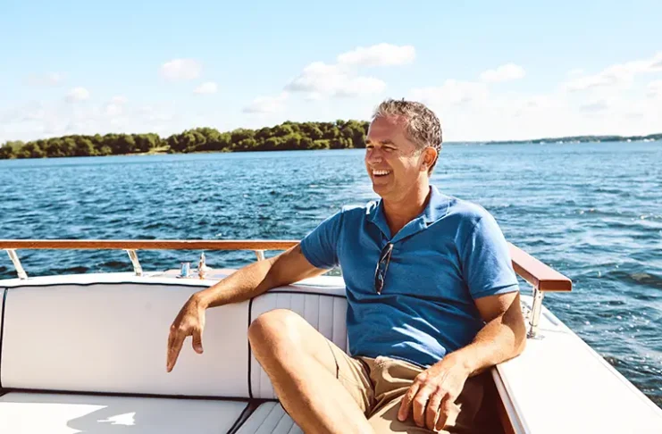 Smiling man relaxing on a boat in Florida waters, enjoying hassle-free boating without ownership on a sunny day.