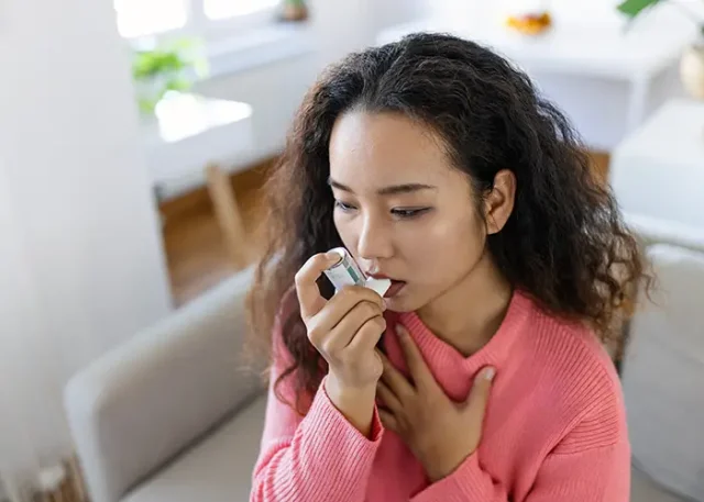 asian-woman-using-inhaler-while-suffering-from-asthma-home-young-woman-using-asthma-inhaler-closeup-young-asian-woman-using-asthma-inhaler-home copy