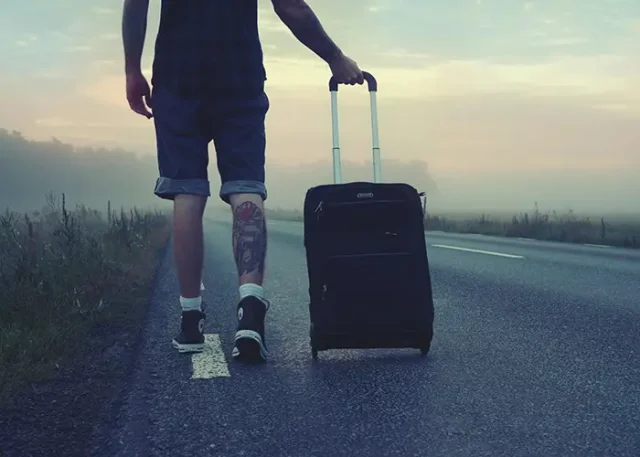 A person walking with a suitcase on the road
