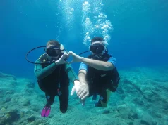 Why the Maldives is one of the most peaceful places on earth for night diving two people scuba diving underwater, making a heart shape with their hands.