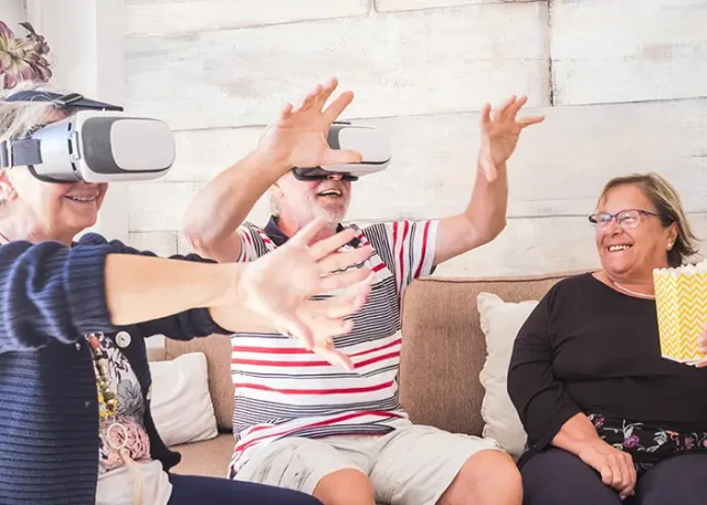 senior-couple-looking-through-virtual-reality-simulator-while-sitting-sofa copy