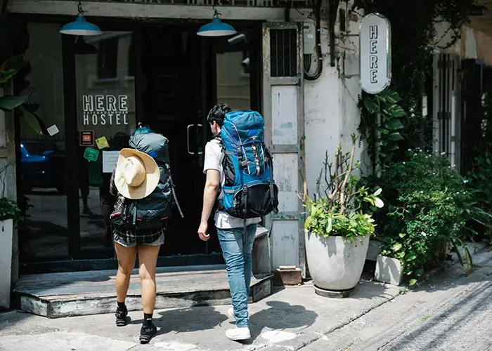 couple entering a hostel while traveling on a budget