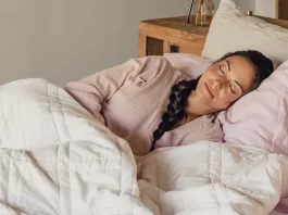 Woman peacefully sleeping under a white quilt on a cozy bed.