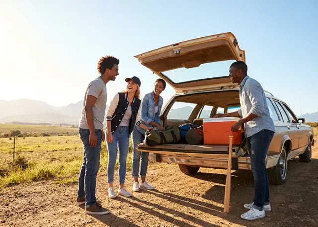A diverse group preparing for a road trip with their car.