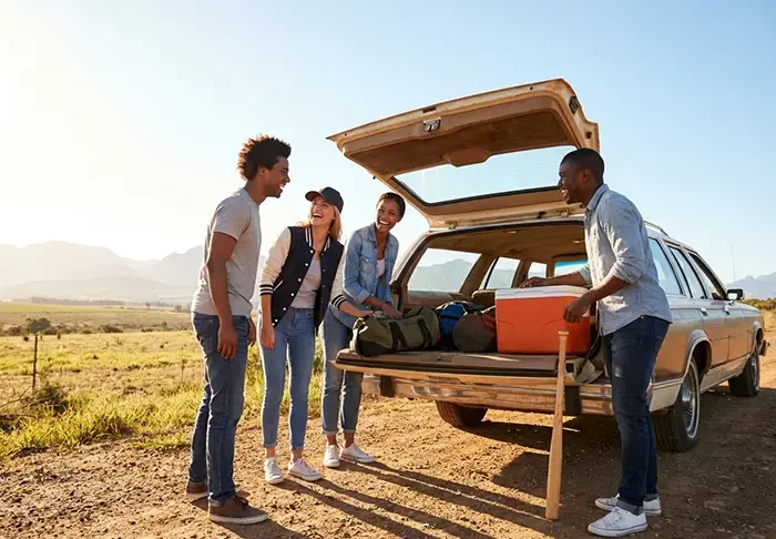 A diverse group preparing for a road trip with their car.