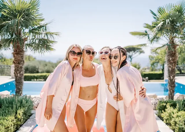laughing-bride-bridesmaids-standing-by-pool-leaning-forward copy