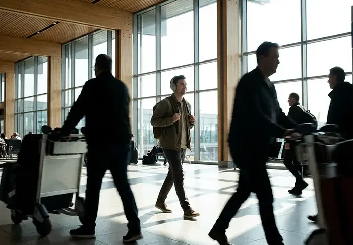 People walking in an airport terminal with large windows.