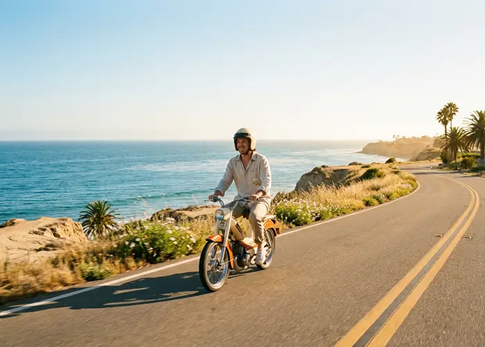 person riding moped on scenic coastal road at sunset.