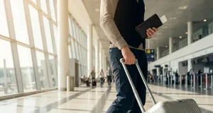 4 Simple Habits For Instant Travel Confidence A person walking in an airport with a suitcase and a passport.
