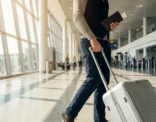 4 Simple Habits For Instant Travel Confidence A person walking in an airport with a suitcase and a passport.