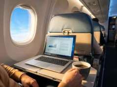 5 Work Travel Essentials for Staying Productive Anywhere Person working on a reliable laptop with coffee in airplane