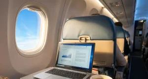 5 Work Travel Essentials for Staying Productive Anywhere Person working on a reliable laptop with coffee in airplane