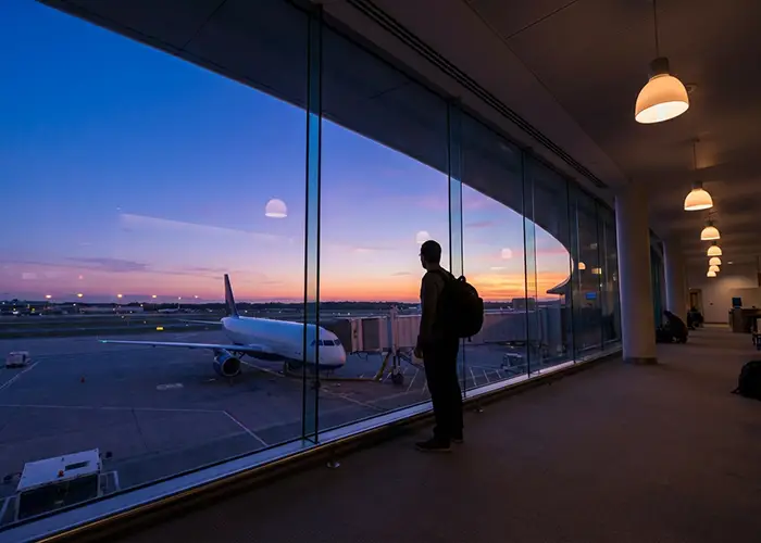 silhouette of traveler looking at plane at sunset