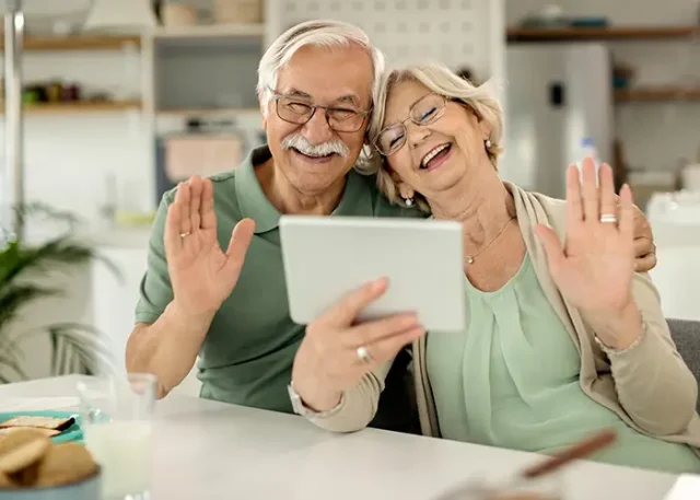 cheerful-mature-couple-waving-video-call-touchpad copy