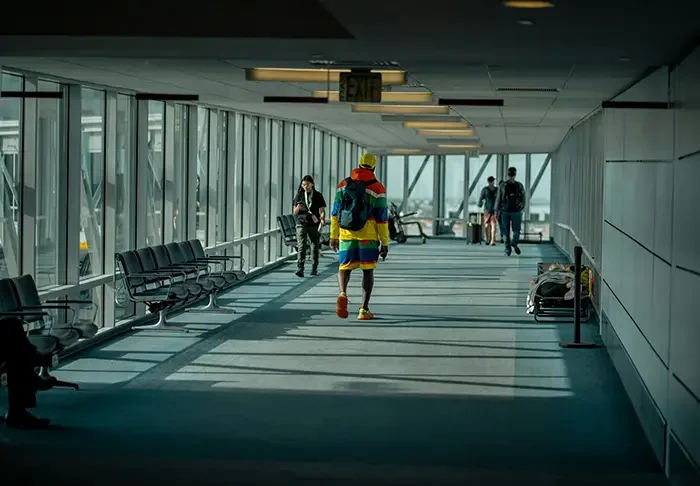 a man walking down a long airport hallway with lots of windows