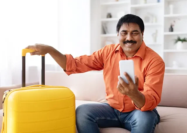 happy-mature-indian-man-using-smartphone-book-vacation-online copy