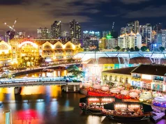 How Singapore Became One of Southeast Asia’s Best Cities for Japanese Food The Singapore River glowing lights at night with the city skyline illuminated in the background.
