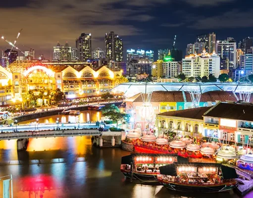 How Singapore Became One of Southeast Asia’s Best Cities for Japanese Food The Singapore River glowing lights at night with the city skyline illuminated in the background.