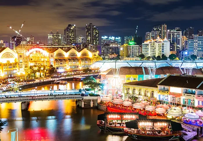 The Singapore River glowing lights at night with the city skyline illuminated in the background.