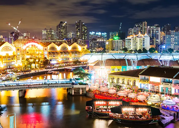 The Singapore River glowing lights at night with the city skyline illuminated in the background.