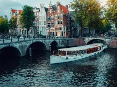 How to elevate your Amsterdam experience with the ultimate luxury event on the water Amsterdam canals with white cruise boat bridge and typical dutch houses