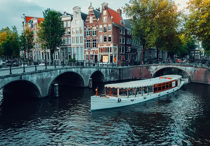 Amsterdam canals with white cruise boat bridge and typical dutch houses