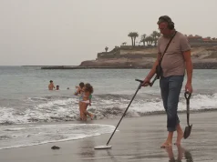 Beach Treasure Hunting: Essential Gear Man with metal detector on a beach